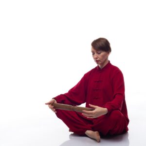 Vrouw in rood chinees gewaad leest de wijsheden van Qigong