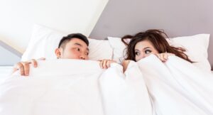 man en vrouw in bed onder een wit dekbed