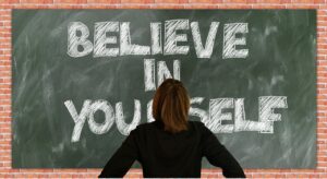 Versterk je zelfvertrouwen. Geloog in je zelf in het engles op een schoolbord geschreven.